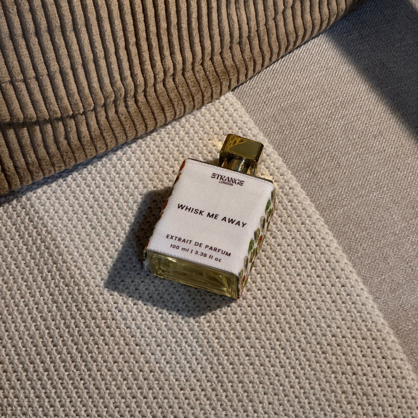 Perfume bottle labeled 'Whisk Me Away' on a textured surface